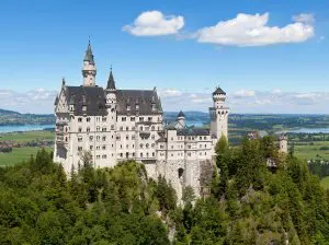 Neuschwanstein Castle rising above forested hillside in the Bavarian Alps