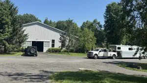 A white dually truck and gooseneck horse trailer parked at the barn, loaded and ready to drive to JFK