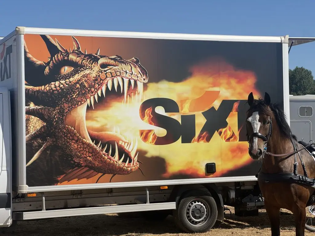 The rented Sixt box truck wrapped in a giant fire-breathing dragon graphic, with Loretta the bay mare standing alongside it at the Chablis CDE.